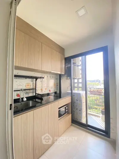 Modern kitchen with sleek cabinetry and balcony access, featuring a bright and airy design.