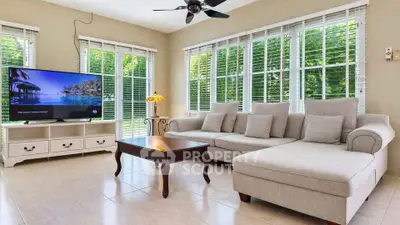 Spacious living room with large windows and modern furniture, offering a serene garden view.