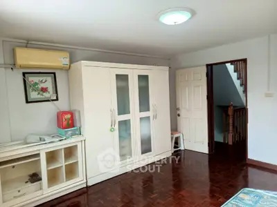 Spacious bedroom with wooden flooring and ample storage space
