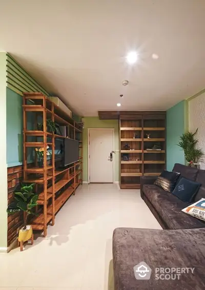 Cozy living room with wooden shelving units, comfortable seating, and tasteful green accent walls, perfect for relaxation and entertainment.