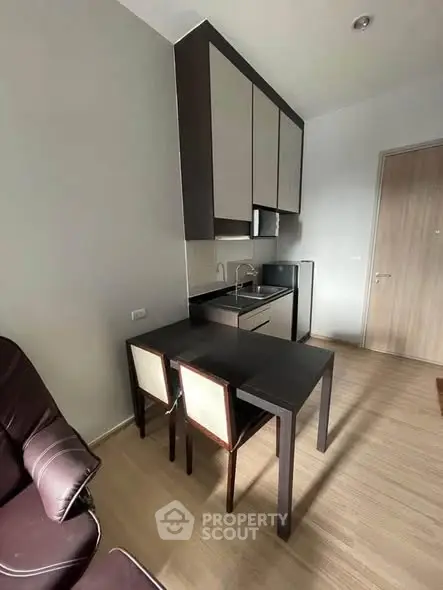 Modern compact kitchen with sleek cabinets and dining area in cozy apartment