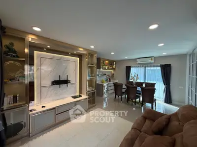 Spacious modern living room with elegant decor and dining area, featuring built-in shelves and large windows.