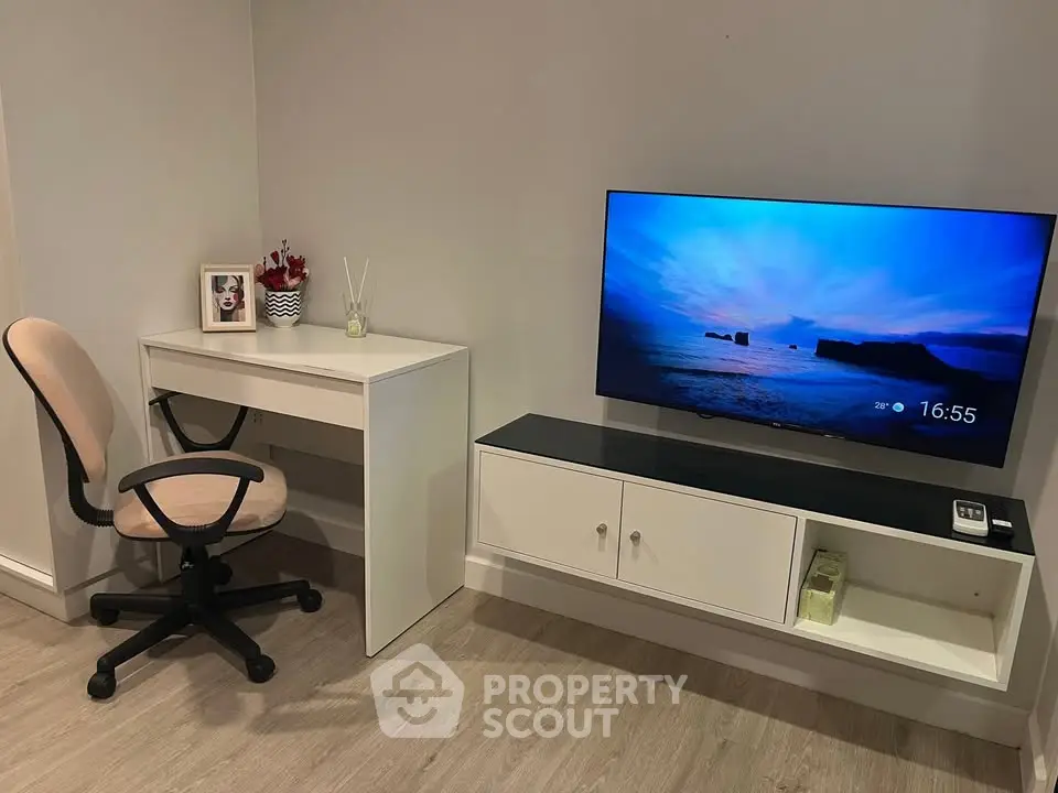 Modern living room with sleek TV setup and stylish desk area, perfect for a cozy home office.