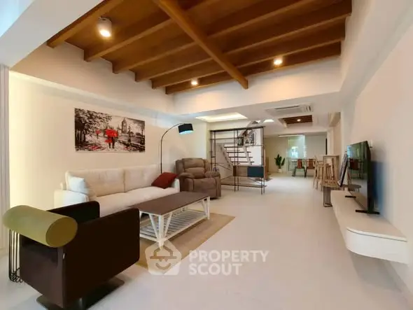 Spacious modern living room with stylish furniture and wooden ceiling beams.