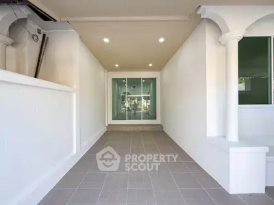 Spacious covered entrance with elegant columns and modern lighting