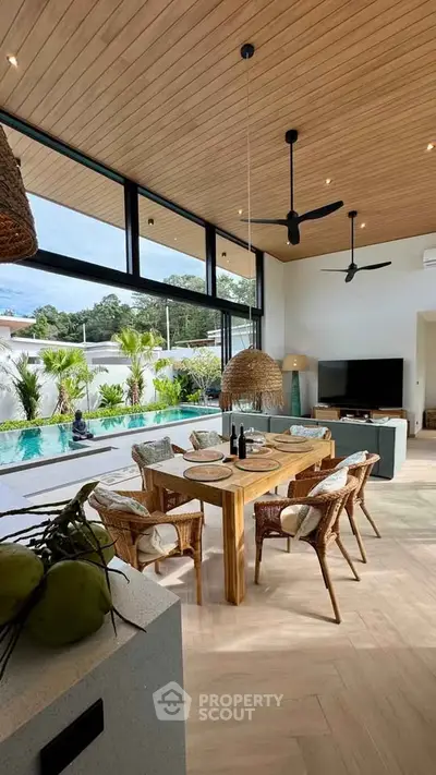 Luxurious open-plan living room with pool view, featuring elegant wooden dining set and modern decor.