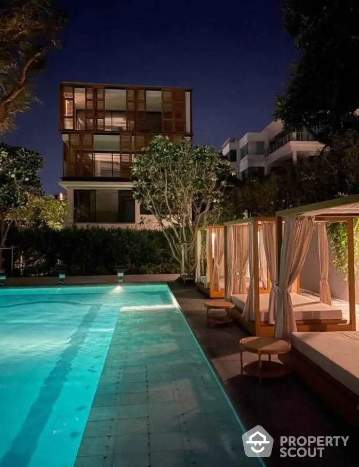 Luxurious night view of modern apartment with illuminated pool and cabanas