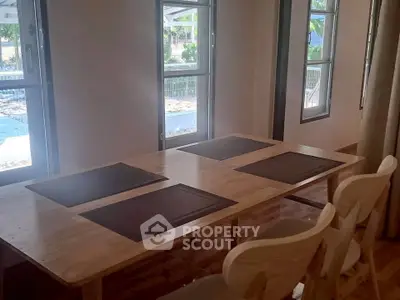 Spacious dining area with wooden table and chairs, featuring large windows for natural light.