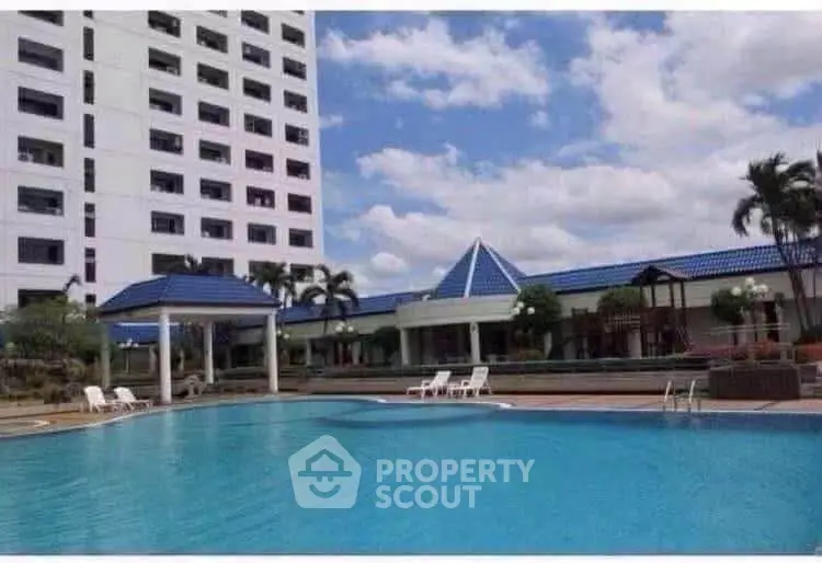 Luxurious residential complex with a stunning pool and modern architecture under a clear blue sky.