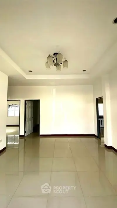 Spacious empty living room with elegant chandelier and tiled flooring