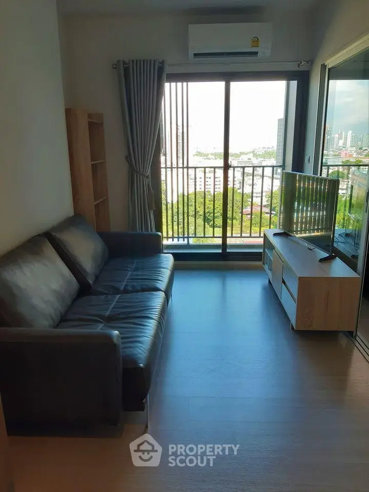 Modern living room with leather sofa and city view balcony in high-rise apartment.