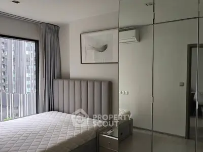 Modern bedroom with mirrored closet and city view, featuring sleek design and natural light.