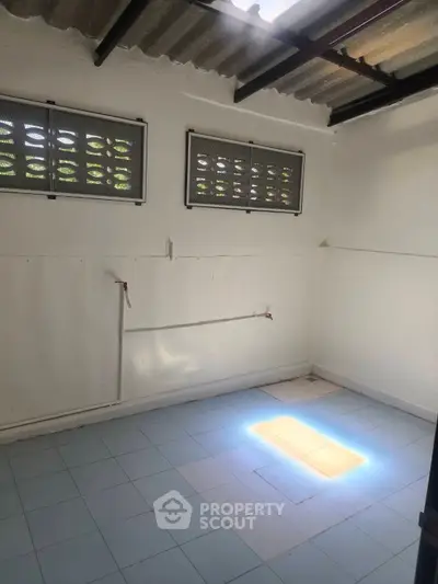 Spacious utility room with tiled floor and natural light, ideal for storage or laundry setup.