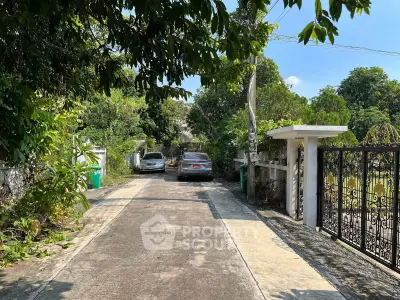 Charming driveway entrance with lush greenery and secure gate access.