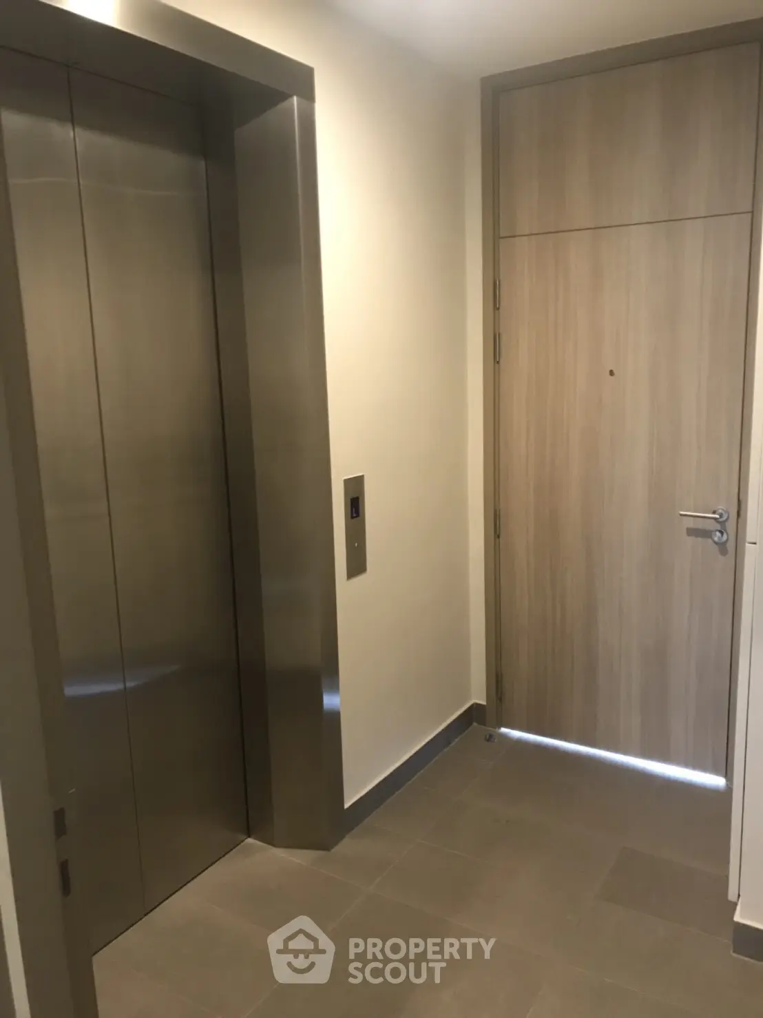 Modern apartment entrance with sleek elevator and wooden door