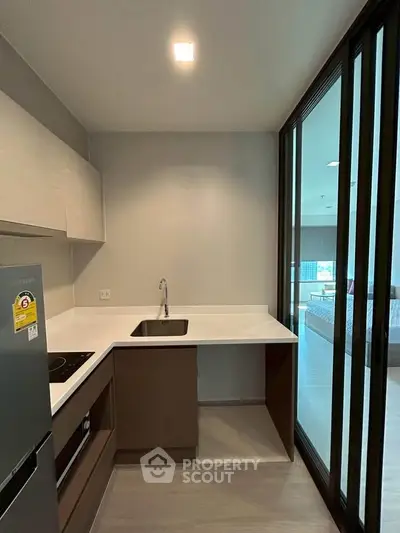 Modern kitchen with sleek design, featuring built-in oven and glass sliding doors for natural light.
