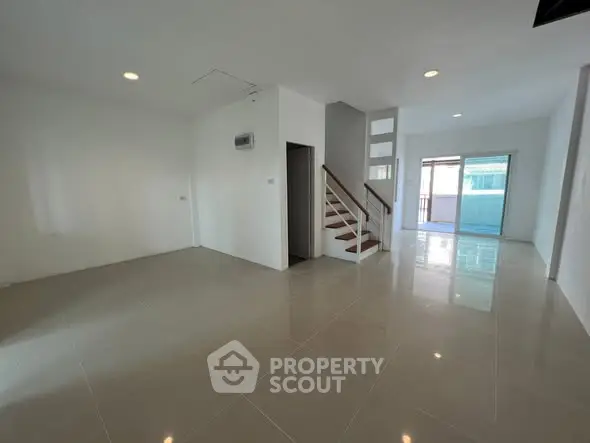 Spacious modern living room with sleek tile flooring and staircase, perfect for family gatherings.