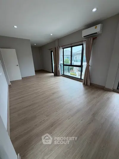 Spacious empty room with large windows and wooden flooring, perfect for customization.