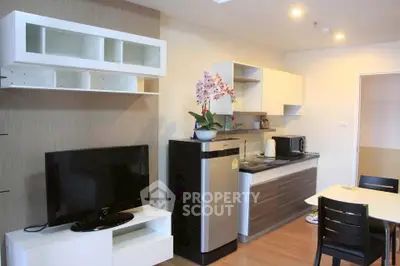 Modern kitchen with sleek cabinets, stainless steel fridge, and cozy dining area.