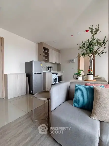 Modern open-plan living room with kitchen, featuring sleek appliances and stylish decor.