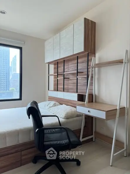 Modern bedroom with city view, featuring stylish storage and workspace.