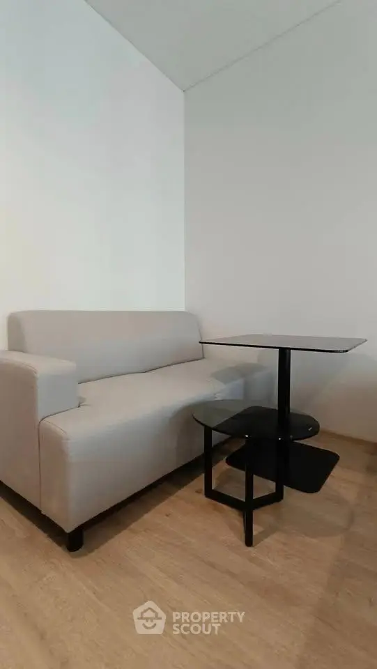 Modern minimalist living room with sleek sofa and stylish side table on wooden flooring.
