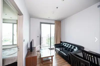 Modern living room with sleek black sofa and balcony view in urban apartment