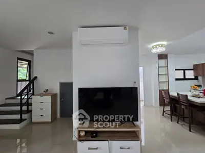 Modern living room with sleek TV setup and open kitchen layout, perfect for contemporary living.