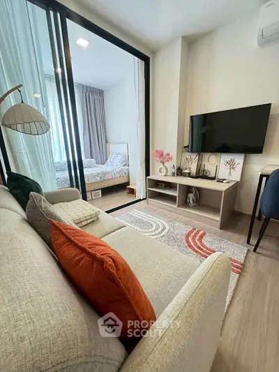 Modern living room with cozy sofa, stylish decor, and view into a chic bedroom