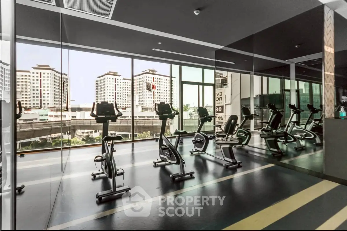 Modern gym with city view and state-of-the-art exercise bikes in luxury apartment building.