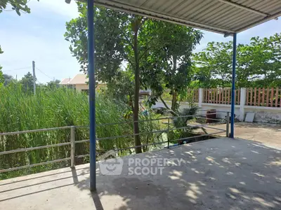 Spacious outdoor terrace with lush greenery and partial roof cover