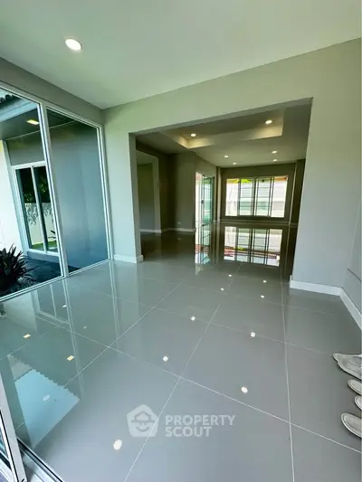 Spacious modern living room with glossy tiled floors and large windows for natural light.