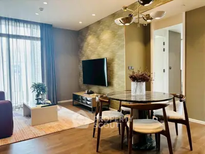Modern living room with stylish dining area and large TV, featuring elegant decor and natural light.