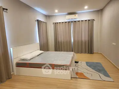Spacious bedroom with modern decor and natural light, featuring a stylish bed and elegant curtains.