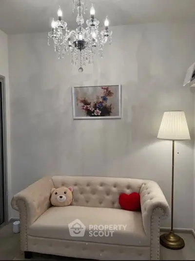 Charming living room with elegant chandelier and cozy sofa, perfect for relaxation.