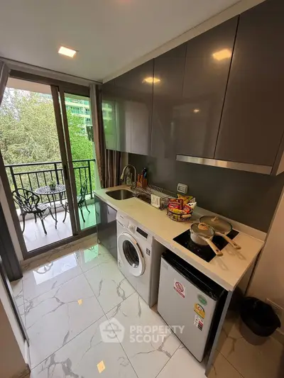 Modern kitchen with sleek cabinets, washing machine, and balcony view, perfect for urban living.