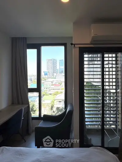 Modern bedroom with city view and balcony access, featuring sleek furniture and large windows.