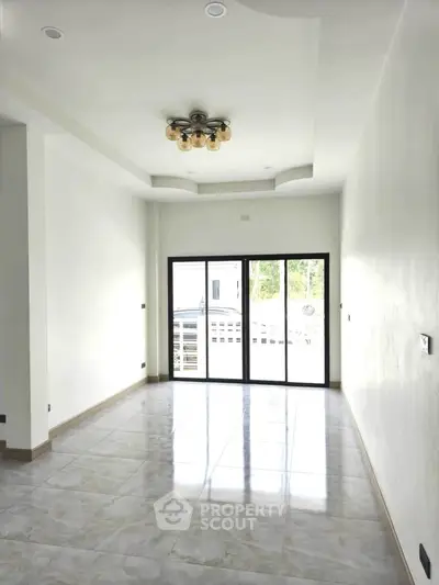 Spacious living room with elegant ceiling light and large windows for natural light.