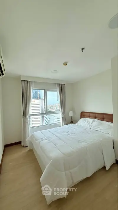 Bright and cozy bedroom with city view, featuring a comfortable bed and modern decor.