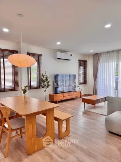 Modern living room with wooden furniture and large windows, featuring a cozy ambiance and stylish decor.