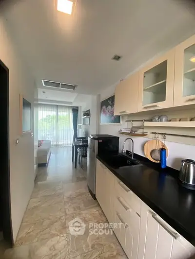 Modern kitchen with sleek cabinets and open layout leading to a bright living area.
