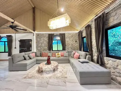 Luxurious living room with high ceilings, stone walls, and elegant chandelier in a modern home.
