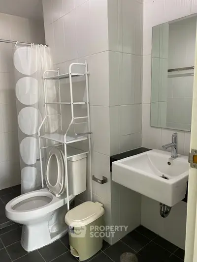 Modern bathroom with sleek fixtures and white tiles, featuring a compact sink and toilet.