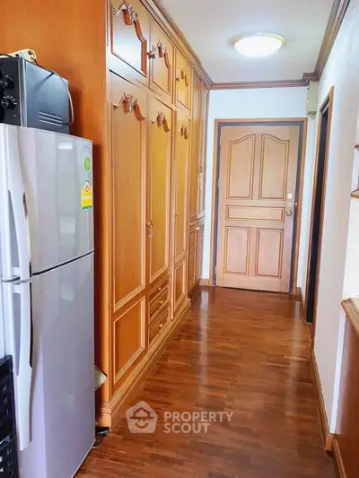 Charming hallway with wooden cabinetry and modern fridge in cozy apartment