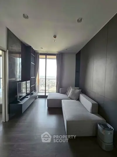 Modern living room with sleek design and large window offering natural light and balcony access.