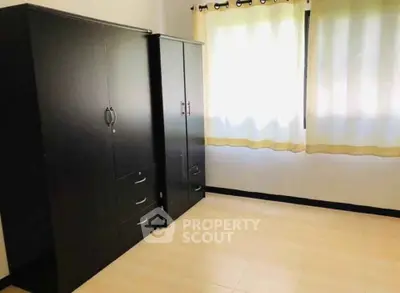 Spacious bedroom with ample natural light and sleek black wardrobes.