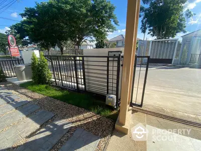 Modern gated entrance with sleek metal design and lush greenery