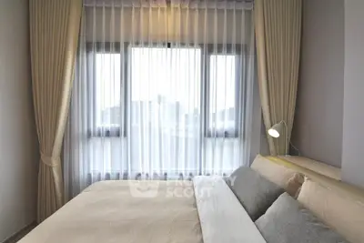 Cozy bedroom with large window and elegant curtains, perfect for relaxation.