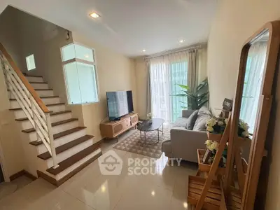 Charming living room with cozy sofa, modern TV setup, and elegant staircase in a bright, airy space.