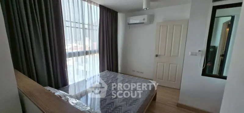 Modern bedroom with large window and stylish decor in a contemporary apartment.